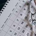 Brown framed eyeglasses on a calendar.
